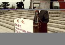 94년도 총학 출범식 (1994), 김익동 총장 연설 사진, 연단 앞에 '식순 축하공연 과노래패 연합공연, 시낭송'이라고 적힌 종이가 붙어있음